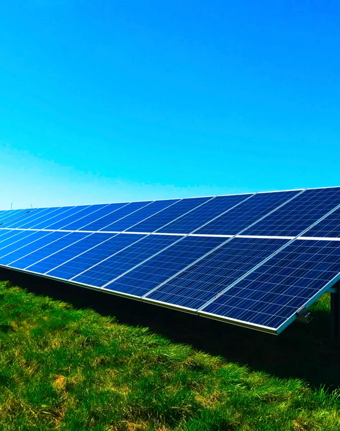 Pole uprawne z niebieskimi panelami słonecznymi pozyskującymi energię słoneczną. Przyjazne dla środowiska kolektory solarne w malowniczym otoczeniu.